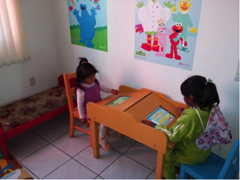Two little girls play games on the tablets under the watchful eyes of Cookie Monster and a number of Sesame Street characters!