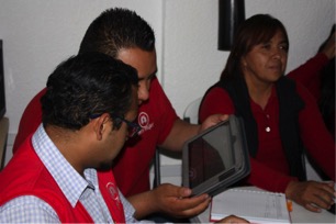 Loan officers Emmanuel and Eric review different ILCB application categories on the tablet used to process loan requests.